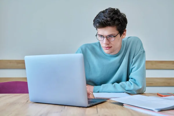 年轻的大学生坐在课桌前 用笔记本电脑 用笔记本写作 语言课程 青年概念 — 图库照片
