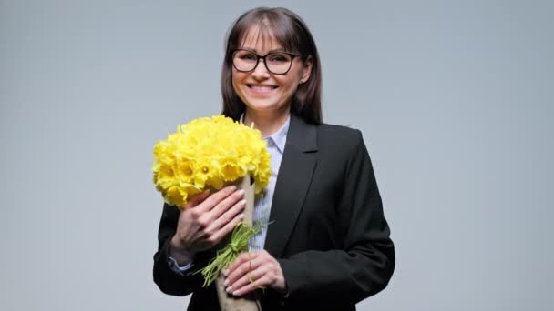 Szczęśliwy Uśmiechnięty Bizneswoman Średnim Wieku Bukietem Żółtych Kwiatów Szarym Tle — Wideo stockowe