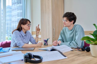 Bayan öğretmen akıl hocası üniversite öğrencisine ders veriyor. Masadaki sınıfta. Eğitim, bilgi, öğrenme, dil kursları, gençlik kavramı