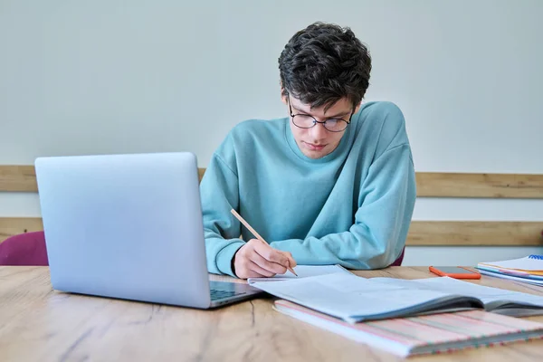 年轻的大学生坐在课桌前 用笔记本电脑 用笔记本写作 语言课程 青年概念 — 图库照片