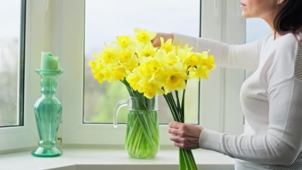 여인들의 꽃병에 꽃꽂이를 조절하고 창가에 수선화를 놓는다 부활절 어머니 아름다운 — 비디오