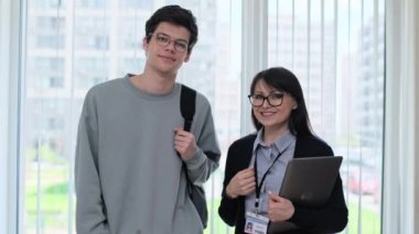 Orta yaşlı bayan öğretmen ve erkek üniversite öğrencisinin portresi. Kadın akıl hocası, özel öğretmen ve koridor eğitim binasının penceresinin yanındaki kameraya bakan adam. Eğitim, öğrenme, dil dersleri, gençlik