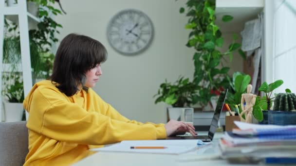 年轻的女大学生坐在家里的办公桌前使用笔记本电脑 18岁19岁的少女在键盘上打字 利用互联网在线技术进行学习 — 图库视频影像