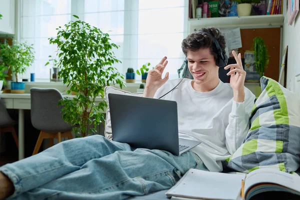 戴耳机的年轻人用笔记本电脑进行视频交流 躺在家里的沙发上 Internet Online Technology Virtual Meetings Modern Lifestyle Learning — 图库照片