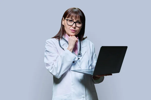 Mature Female Doctor Using Laptop Computer Grey Studio Background Confident — Stock Photo, Image