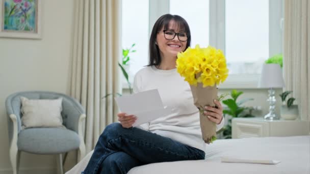 즐거운 흥분을 자아내는 소파에 축하의 편지를 낭독하고 노란색 꽃들을 꽃다발 — 비디오