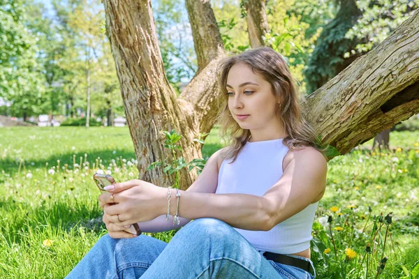 Ung Kvinna Sitter Gräset Parken Koppla Med Smartphone Mobila Applikationer — Stockfoto