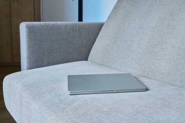 Kapalı dizüstü bilgisayar, arka planda, modern gri bir kanepede. Teknoloji, iş, öğrenim, serbest çalışma, eğlence, yaşam tarzı konsepti