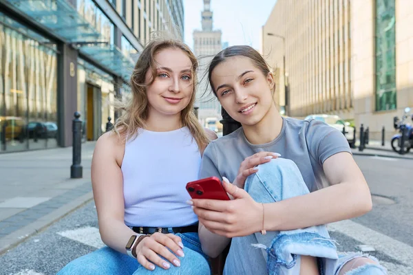 Két Mosolygós Tinédzser Diáklány Okostelefonnal Modern Városi Stílusú Épületekkel Közúti — Stock Fotó