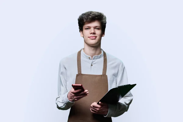 Portret Van Jonge Zelfverzekerde Man Schort Met Papieren Klembord Smartphone — Stockfoto