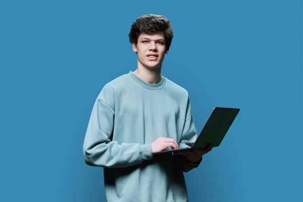 Νεαρός Φοιτητής Που Χρησιμοποιεί Φορητό Υπολογιστή Μπλε Φόντο Στούντιο Χαμογελώντας — Φωτογραφία Αρχείου
