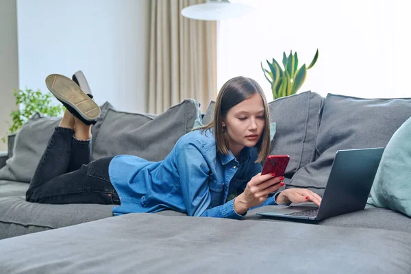 소녀는 스마트폰을 사용하여 행복하게 거실의 소파에 있습니다 인터넷 온라인 서비스 — 스톡 사진