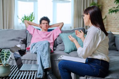 Genç bir erkek psikolog muayenehanesinde zihinsel terapi görüyor. Adam üniversite öğrencisi terapistle konuşuyor, kadın danışman konuşuyor, not tutuyor. Psikoterapi kavramını destekle