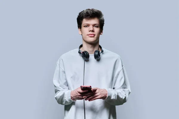 Νεαρός Όμορφος Άντρας Ακουστικά Που Κρατάνε Smartphone Γκρι Φόντο Στούντιο — Φωτογραφία Αρχείου