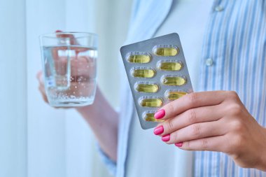 Omega 3 balık yağı kapsüllerine yaklaşırken kadınların elinde bir bardak su vardı. Besin takviyeleri diyeti, güzellik sağlığı cilt kılları, günlük yaşam tarzı, sağlık hizmetleri, vitamin d, e, a,