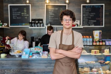 Kafe çalışanları, odak noktasında önlüklü genç bir adam. Küçük işletme kafeteryası kahve evi, iş, iş, personel konsepti