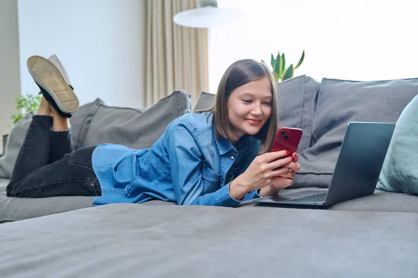 소녀는 스마트폰을 사용하여 행복하게 거실의 소파에 있습니다 인터넷 온라인 서비스 — 스톡 사진