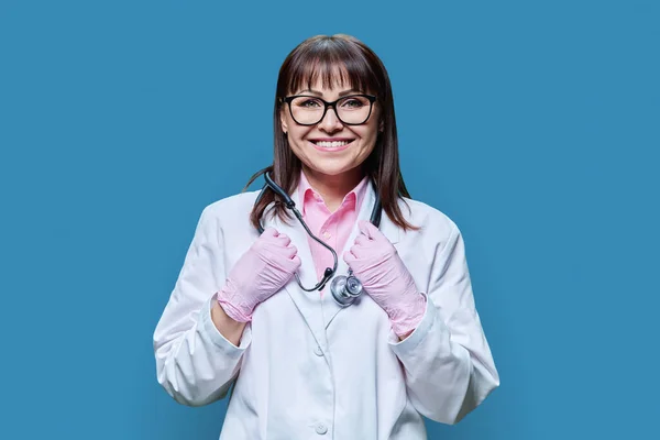 中年妇女医生的画像 身穿白色实验室外套手套听诊器 在蓝色工作室背景下看着相机 医药健康保护 专业医务工作者 医疗服务概念 — 图库照片