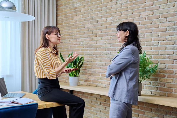 Дві Зрілі Ділові Жінки Розмовляють Сучасному Офісі Сміючись Спілкуватися Колегою — стокове фото