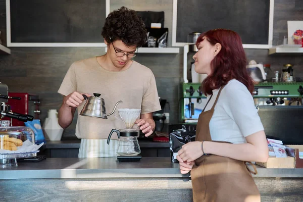 若いコーヒーショップの労働者は 男性と女性のエプロン話を着て カフェテリアでカウンターの前に立っている フードサービスの職業 スタッフのアルバイト 仕事のコンセプト — ストック写真
