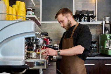 Kahve dükkanında kahve hazırlayan erkek barmen, kahve makinesinin yanında duran önlüklü, sakallı genç adam. Küçük işletme, yemek servisi işi, kahve dükkanı, personel, iş konsepti