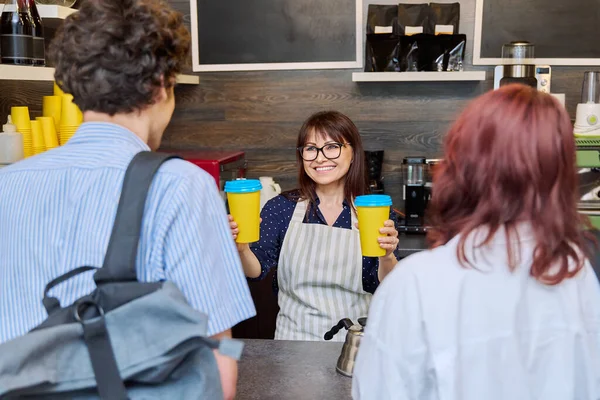 女咖啡店工作人员为一对年轻顾客提供纸杯外卖咖啡 食品服务职业 小企业 人的概念 — 图库照片