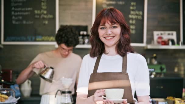 Портрет Молодої Усміхненої Жінки Офіціантки Фартусі Тримає Чашку Кави Стоїть — стокове відео