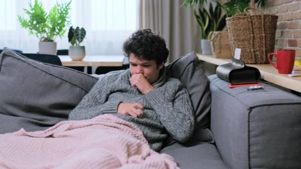 남자가 기침을 호흡기 감염의 징후를 보이고 스웨터를 소파에 있습니다 — 비디오
