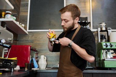 Kahve dükkanında kahve hazırlayan erkek barmen, kahve makinesinin yanında duran önlüklü, sakallı genç adam. Küçük işletme, yemek servisi işi, kahve dükkanı, personel, iş konsepti