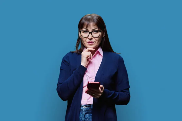 Žena Středního Věku Používá Smartphone Pozadí Modrého Studia Vážná Čtyřicátnice — Stock fotografie
