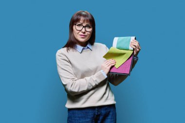 Mavi arka planda iç dekoratif kumaş örnekleri olan bir kadın. Kumaş gösteren kadın tasarımcı, perde döşemesini seçen alıcı. Tekstil tasarımı, biçim tasarımı dekoru