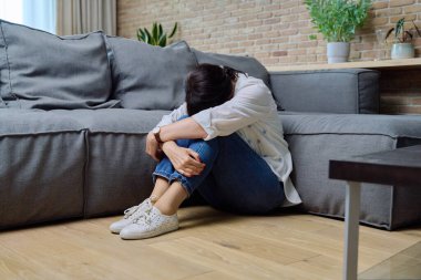 Fiziksel acı çeken olgun bir kadın, zihinsel sorunlar. 50 'li yaşlarda kadın. Oturma odasında, koltuğun yanında oturuyor. Sorunlar, yalnızlığı, yaşla ilgili değişiklikleri, sağlık kavramını vurgular