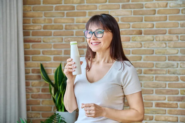 Medelålders Kvinna Dricker Fermenterad Mjölkprodukter Från Flaskan Hemma Nära Fönstret — Stockfoto