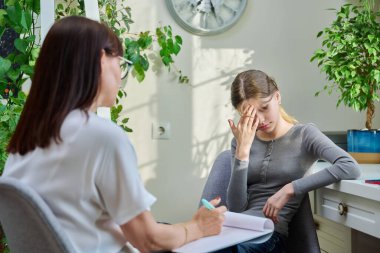 Terapide psikologla görüşen üzgün genç kız, avukat. Üzgün bir kız, lise öğrencisi, akıl hastanesinde oturuyor. Çocuk psikolojisi, psikoterapi, gençlerin sosyal hayatı.
