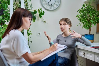 Terapide psikologla görüşen üzgün genç kız, avukat. Üzgün bir kız, lise öğrencisi, akıl hastanesinde oturuyor. Çocuk psikolojisi, psikoterapi, gençlerin sosyal hayatı.