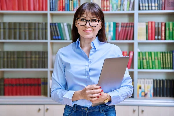 stock image Portrait of confident female teacher mentor counselor social worker educator holding laptop inside library in educational building. Female professional education training sociology mental health