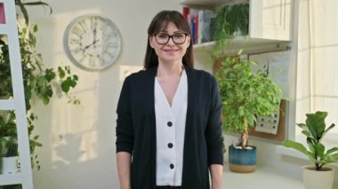 Merkez ofisteki kameraya bakan orta yaşlı zarif, kendine güvenen bir kadın. Kollarını kavuşturmuş başarılı, olgun bir dişi. Çalışma, iş, eğitim, öğretim, olgun insanlar kavramı