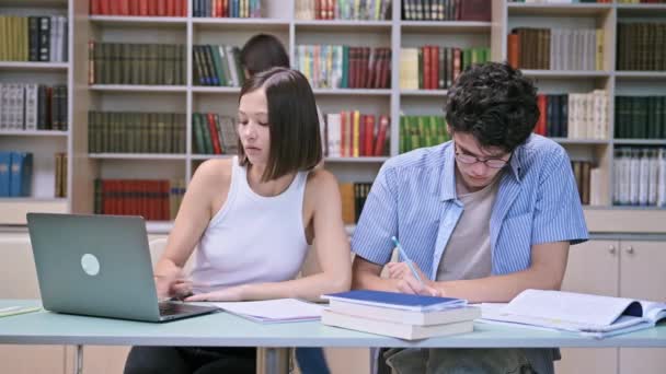 大学図書館の机に座っている若い男性と女性の学生 ノート 試験の準備 大学のコンセプト — ストック動画