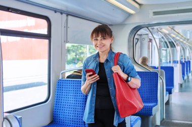 Orta yaşlı kadın rahat bir elektrikli tren vagonunda yolcu. Şehir içi elektrik taşımacılığı, şehirlerarası ulaşım, demiryolu konsepti