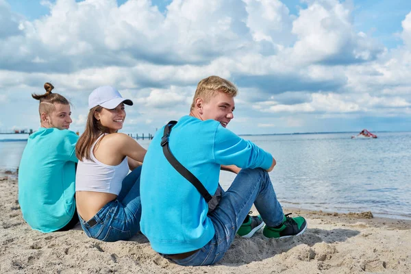 Visão Traseira Três Amigos Adolescentes Sentados Areia Praia Olhando Para — Fotografia de Stock