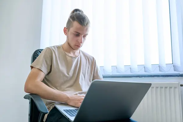 十几岁的男生19 20岁坐在家里的椅子上使用 在电脑笔记本电脑上打字 用于学习通信 闲暇工作 青年概念的数字技术 — 图库照片