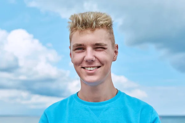 ハンサムな笑顔のティーンエイジャーのヘッドショットの肖像画 雲の中の青い空に対して肯定的な若い男性の顔 歳のライフスタイル 楽しむ アウトドア — ストック写真