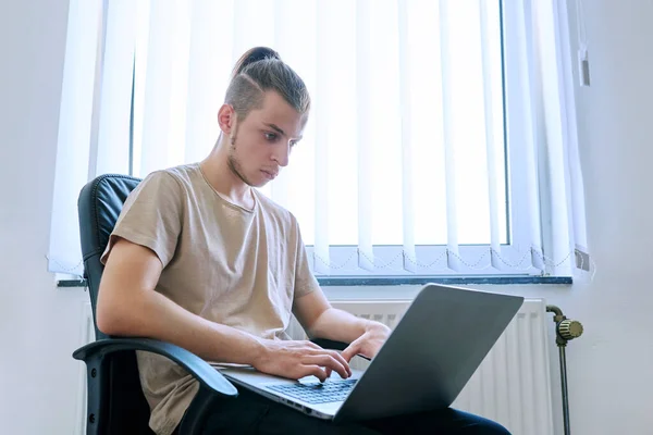 十几岁的男生19 20岁坐在家里的椅子上使用 在电脑笔记本电脑上打字 用于学习通信 闲暇工作 青年概念的数字技术 — 图库照片