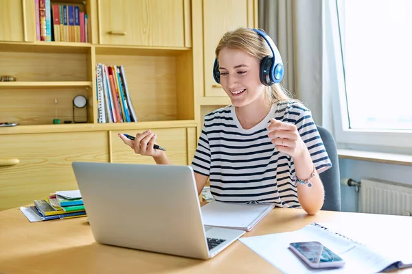 Teenage girl high school student in headphones having video conference on laptop computer at home remote lesson learning language online lecture educational webinar. E-education adolescence technology