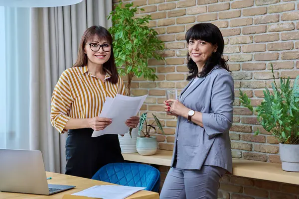 Dwie Dojrzałe Biznesmenki Pracujące Razem Biurze Uśmiechnięte Kobiety Patrzące Kamerę — Zdjęcie stockowe