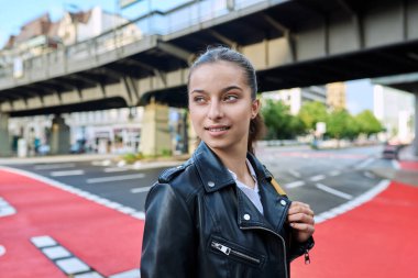 Genç lise öğrencisinin portresi. 16-17 yaşlarında, sırt çantalı, modern şehrin sokaklarında kameraya bakan kendine güvenen bir kız. Şehir hayatı, ergenlik, eğitim, gençlik kavramı