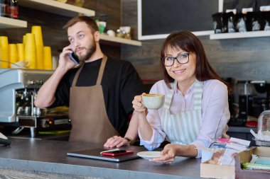 Takım, ortaklar, genç bir erkek ve olgun bir kadın barın arkasında telefonla konuşuyor. Takım, küçük işletme, iş, personel, kafeterya restoranı, girişimcilik konsepti