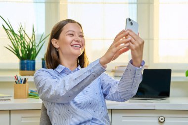 Ağ için video blogu kaydeden akıllı telefonlu genç bir kadın. Sosyal medya takipçileriyle iletişim kuran, internetten arkadaşlarıyla konuşan bir kadın. Teknoloji serbest çalışma gençliği