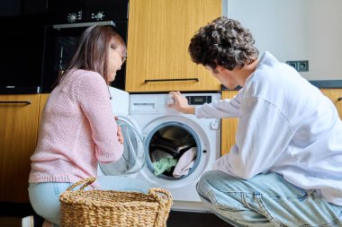 Aile annesi ve genç oğlu birlikte, çamaşır makinesinin yanında, yaşam tarzı, ergenlik, iletişim, ilişkiler, günlük rutin konsept