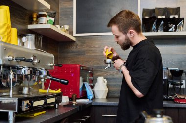 Kahve dükkanında kahve hazırlayan erkek barmen, kahve makinesinin yanında duran önlüklü, sakallı genç adam. Küçük işletme, yemek servisi işi, kahve dükkanı, personel, iş konsepti